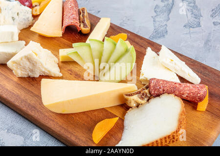 Käseplatte Ansicht von oben. Verschiedene Käsesorten Camembert, Brie, Parmesan Blauschimmelkäse, Ziege. Mit Wurst, Speck, Trauben, Feigen, Äpfeln und Aprikosen serviert. Stockfoto