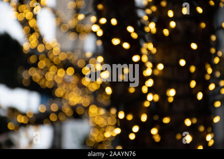 Zusammenfassung Hintergrund gelb bokeh Lichter, Zweige eines Baumes im Winter mit blauem Himmel und Schnee, Landschaft, warmes Gefühl, Weihnachten Stockfoto