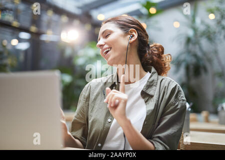 Portrait von unbeschwerte junge Frau, Musik hören und tanzen im Sitzen im Cafe Tisch auf der Terrasse, kopieren Raum Stockfoto