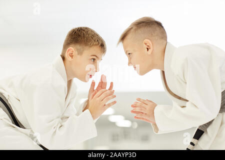 Zwei kleine Jungen im Kimono stehen einander gegenüber und Üben von Streiks in Karate Stockfoto