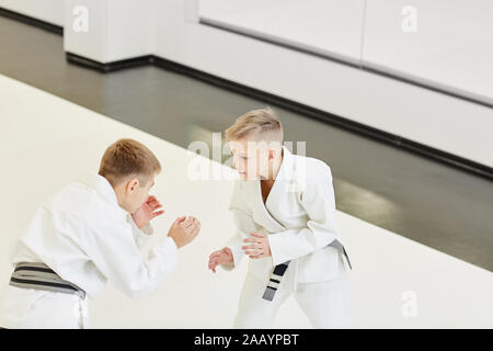 Zwei Männer in weißen Kimono stehen einander gegenüber und kämpfen während der Konkurrenz im Karate in der Turnhalle Stockfoto