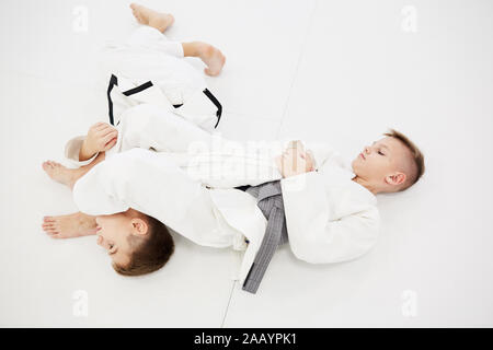 Zwei Jungen im Kimono auf dem Boden kämpfen und konkurrieren miteinander im Wettbewerb im Karate Stockfoto