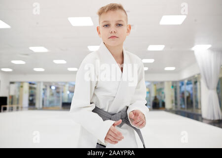 Porträt der Jungen stehen in weißen Kimono an Kamera suchen und bereit für den Kampf in der Turnhalle Stockfoto