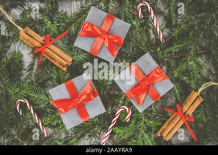 Drei Weihnachtsgeschenke setzte sich auf den Ästen eines Weihnachtsbaum neben Candy Cane und Zimtstange Dekorationen Stockfoto
