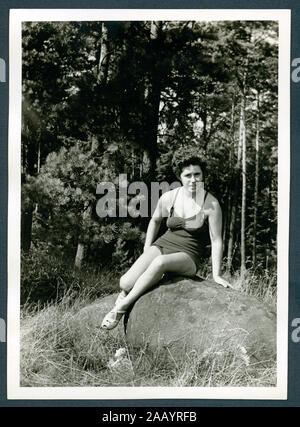 Europa, Deutschland, Hamburg, junge Frau sitzt auf einem Felsen, sie trägt einen Badeanzug, im Hintergrund Wald, 1950er Jahre. / Europa, Deutschland, Hamburg, junge Dame trägt einen Badeanzug, auf einem Stein saß, im Hintergrund gibt es einen Wald, 1950. Stockfoto