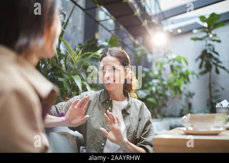Taille bis Portrait von lächelnden jungen Frau im Gespräch mit Freund auf Outdoor Cafe Terrasse, Kopie Raum Stockfoto