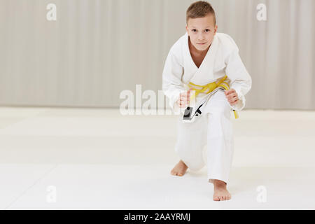 Portrait von kleinen Jungen in weißen Kimono bereit für den Kampf, den er stehen und von der Kamera Stockfoto