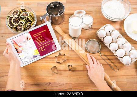 Flache Layout der Hände der jungen Hausfrau holding Tablet und Rolling Pin beim Gehen Gebäck zu Hause zu kochen Stockfoto