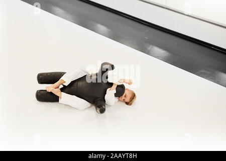 Der Junge im Kimono auf dem Boden liegen und die Technik der Kampf mit Mannequin während der Lektion im Karate Stockfoto