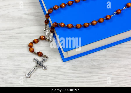 Rosenkranz mit braunen Körner liegen auf einem Buch auf einem weißen Tisch Stockfoto