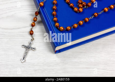 Rosenkranz mit braunen Körner liegen auf einem Buch auf einem weißen Tisch Stockfoto