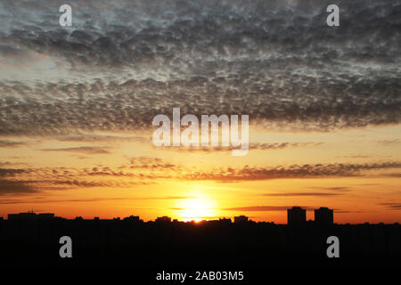 Sonnenuntergang über der Stadt. Strahlende Sonne und orange sky mit dunklen Wolken über Wohngebäude, malerischen Blick Stockfoto