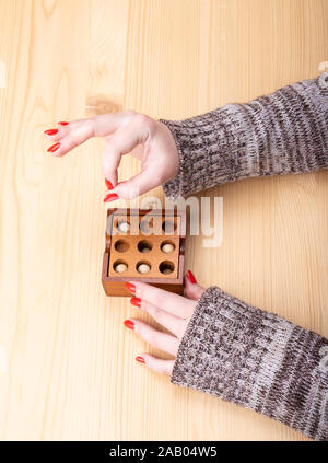 Das Mädchen zeigt ein OK-Zeichen an den Fingern nach der Erhebung der Puzzle. Holzpuzzle Kugeln und Bohrungen. Helle Maniküre auf Fingernägeln. Puzzle Konzept. Stockfoto