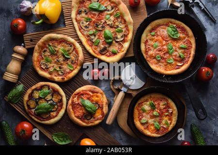 Gesunde vegetarische Nahrung flatlay. Hausgemachte rustikale Pizza mit Tomaten, Pilze, Auberginen und Basilikum mit Zutaten aus Gusseisen Pfannen und Eiche b Stockfoto