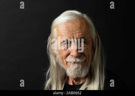 Portrait von schönen alten Mann mit langen grauen Haaren. Der Mann lächelt und Suchen auf der rechten Seite des Fotos. Stockfoto