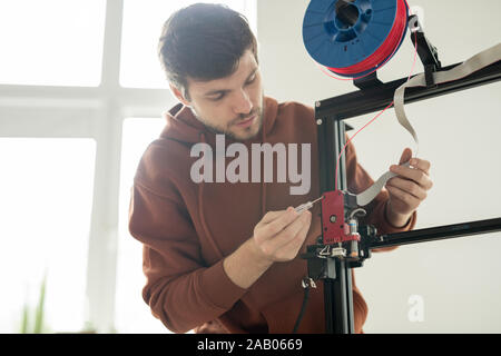 Junge Ingenieur mit Schraubendreher Instandsetzung druckkopf von 3d Drucker oder zur Festsetzung der Rückseite vor Arbeiten Prozess Stockfoto