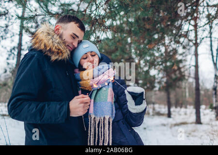 Paar brennende Wunderkerzen im Winter Wald. Weihnachten und Neujahr Konzept. Die Menschen feiern Feiertage Stockfoto