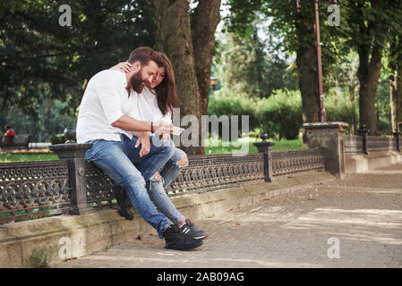 Junges Paar an einem Smartphone an einem sonnigen Tag in der Stadt suchen Stockfoto