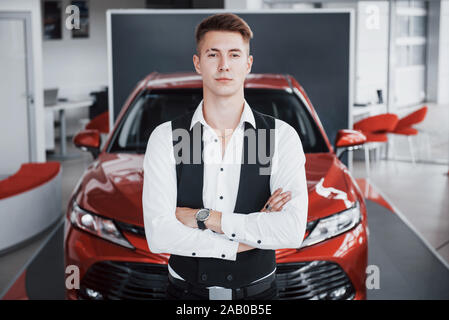 Ein junger gut aussehender Geschäftsmann steht mit dem Auto Stockfoto