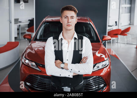Ein junger gut aussehender Geschäftsmann steht mit dem Auto Stockfoto