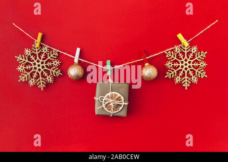 Weihnachten handgefertigte Girlande aus goldenen Schneeflocken und anderen Weihnachtsschmuck auf rotem Hintergrund. Stockfoto