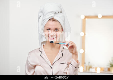 Hübsche junge Frau mit Zahnbürste durch ihren Mund vor der Kamera Stockfoto