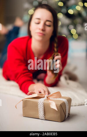 Tief unter dem Blickwinkel - Foto von charmanten nett schön attraktives Mädchen mit einem Geschenk in Jeans und Pullover rot