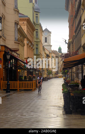 Vaci utca in Budapest, einzelne Radfahrer reiten unter dem Regen Stockfoto