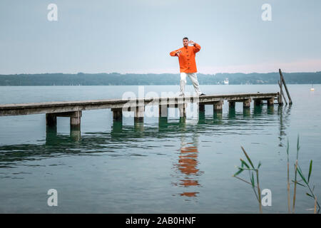 Ein Mann, der am fruehen Morgen Qi-Gong-Uebungen am Starnberger See durchfuehrt Stockfoto