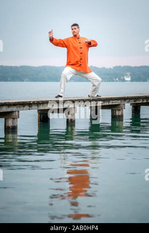 Ein Mann, der am fruehen Morgen Qi-Gong-Uebungen am Starnberger See durchfuehrt Stockfoto