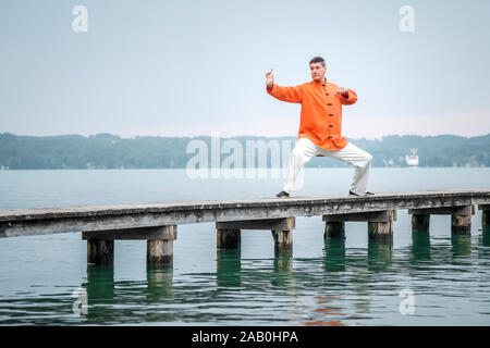 Ein Mann, der am fruehen Morgen Qi-Gong-Uebungen am Starnberger See durchfuehrt Stockfoto