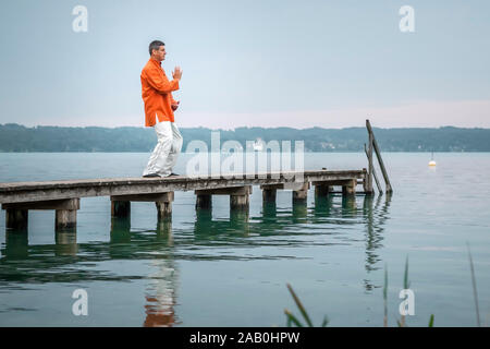 Ein Mann, der am fruehen Morgen Qi-Gong-Uebungen am Starnberger See durchfuehrt Stockfoto