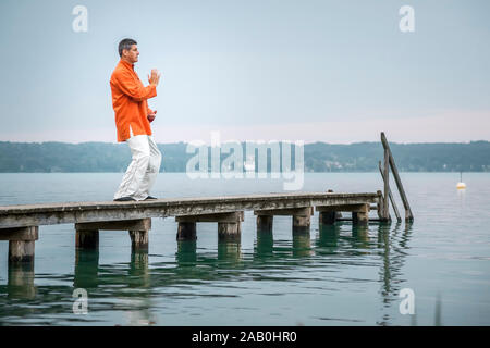 Ein Mann, der am fruehen Morgen Qi-Gong-Uebungen am Starnberger See durchfuehrt Stockfoto