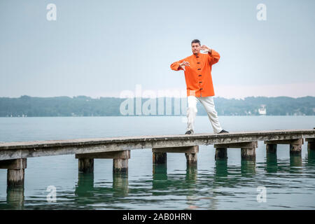 Ein Mann, der am fruehen Morgen Qi-Gong-Uebungen am Starnberger See durchfuehrt Stockfoto