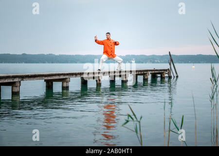 Ein Mann, der am fruehen Morgen Qi-Gong-Uebungen am Starnberger See durchfuehrt Stockfoto