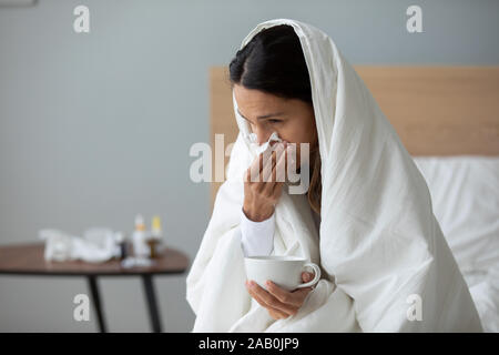 Frau mit Tasse mit heißem Getränk und bläst laufende Nase Stockfoto