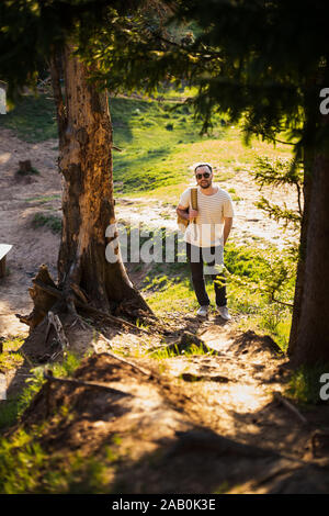 Wandern Menschen Porträt mit Rucksack wandern in der Natur. Kaukasische Mann lächelt zufrieden mit dem Wald im Hintergrund im Sommer Reise Stockfoto