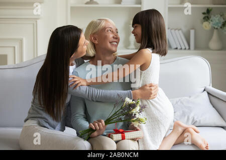 Erwachsener Tochter Enkelin umarmen ihre betagte Großmutter mit dem Geburtstag gratulieren. Stockfoto