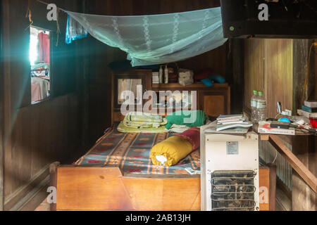 Cai, Mekong Deltal, Vietnam - März 13, 2019: Kleines Schlafzimmer mit Bürotisch und weißen Kühlschrank. Azure Moskitonetz über dem Bett. Kleines Fenster ma Stockfoto