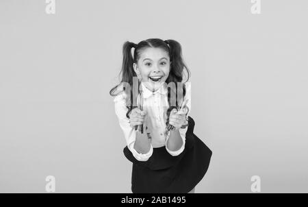 Happy Arts glücklichen kleinen Künstler. Happy girl Holding bunte Markierungen auf gelben Hintergrund. Fröhliches kleines Kind mit glücklichem Lächeln und Stifte. Genießen Sie Kunst und Kunsthandwerk. Stockfoto