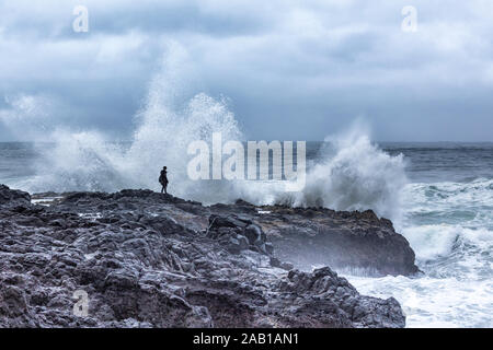 Wave Absturz über Person, die auf Felsen Stockfoto