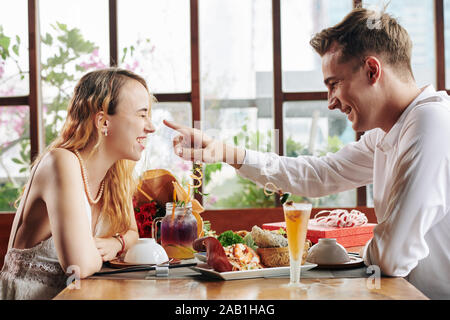 Schön lächelnden jungen Mann an der Spitze der lachende Freundin zeigen Zuneigung beim Abendessen zum Ausdruck zu bringen Stockfoto