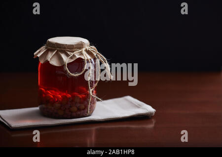 Geschmorten Stachelbeeren und Johannisbeeren in einem Glas. Dunklen Holztisch und Hintergrund. Copyspace. Stockfoto