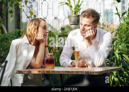 Junges Paar am Tisch im Café im Freien und trinken Cocktails in der ersten Datum Langweilten Stockfoto
