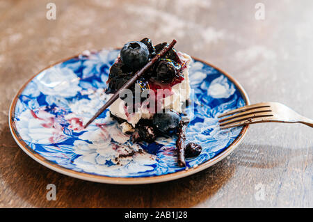 Rich sweet blueberry Käse torte bereits auf schönen Luxus Keramik Teller mit Gabel aus Messing auf Holz Tisch gegessen Stockfoto