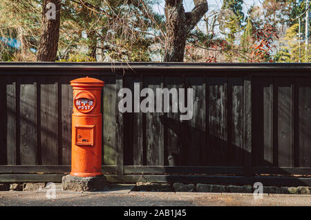 DEC 3, 2018 Hakuba, Japan - rot vintage Japanisch schreiben Postbox und schwarze hölzerne Wand in Hakuba alten Samurai Stadt Akita, Tohoku Region Stockfoto