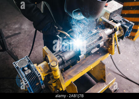 Hish winkel Bild eines Schweißers arbeiten auf Metall Stück, mit industriellen Schelle befestigt Stockfoto