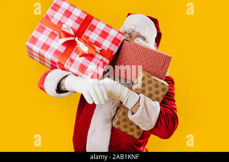 Zufrieden zufrieden Santa Claus mit Händen voller Geschenke, versucht nicht zu tropfen Stockfoto