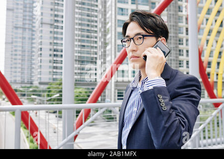 Portrait von Stattlichen schweren jungen asiatischen Unternehmer gehen im Freien und am Telefon sprechen Stockfoto