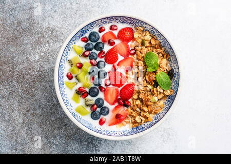 Frühstück smoothie Schüssel mit Obst und Müsli. Superfood Schüssel auf konkreten Hintergrund isoliert. Sauber, Essen, Diät, Gewichtsverlust Konzept Stockfoto